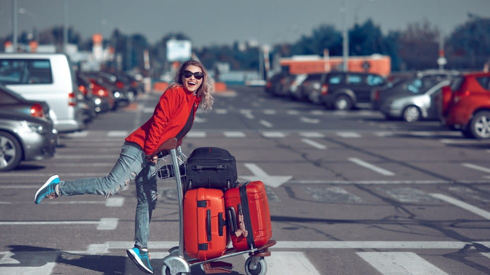 Woman pushing luggage trolley in carpark